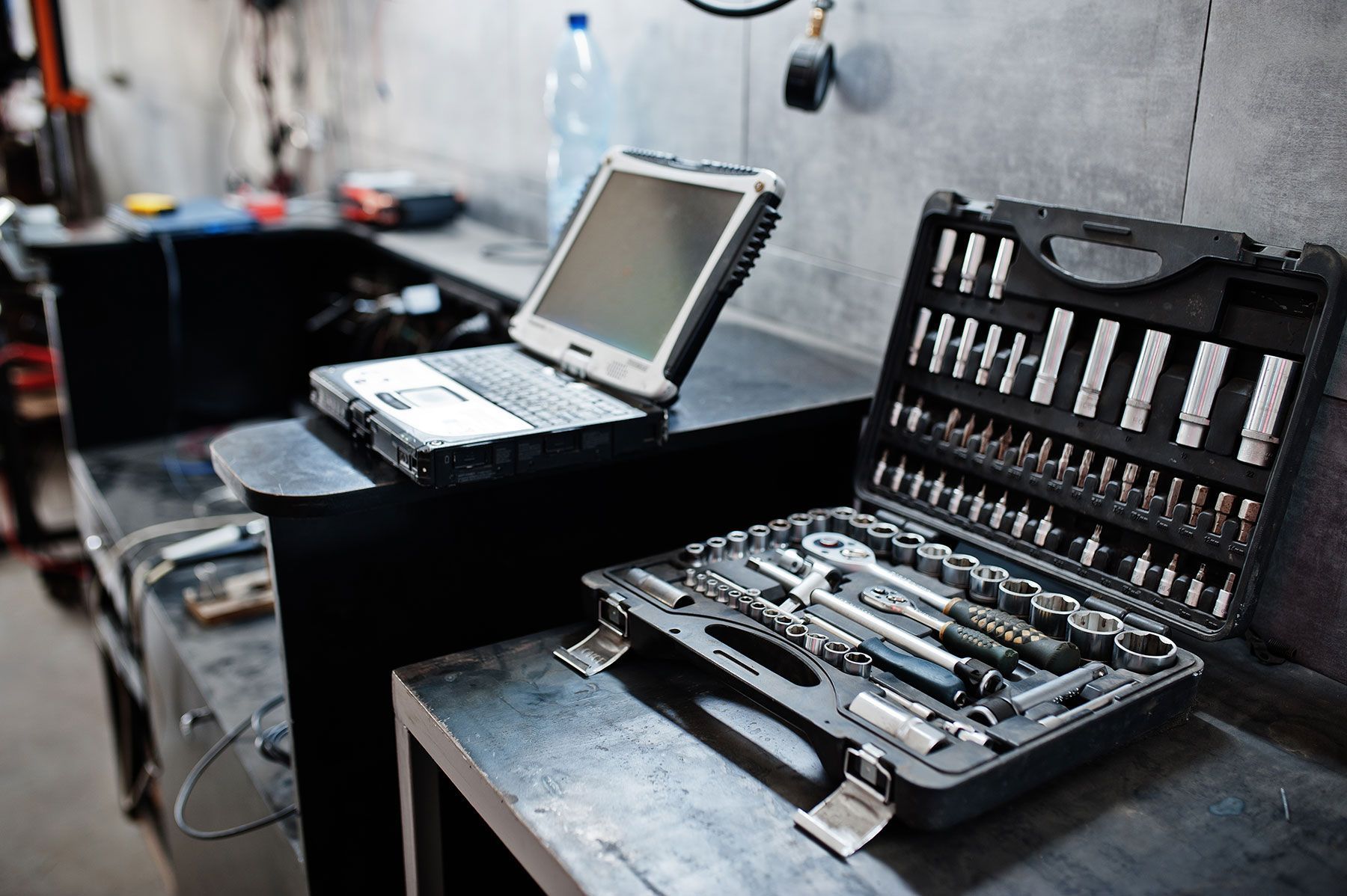 Laptop and open toolbox on a garage workbench.