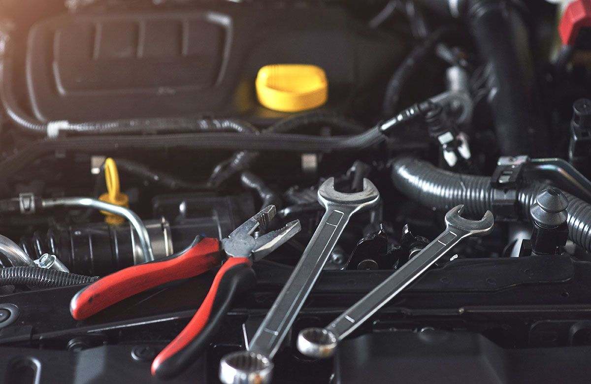 Pliers and wrenches on a car engine, suggesting repair.